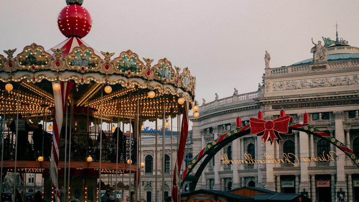 A carousel at a Christmas market in front of a classical building.