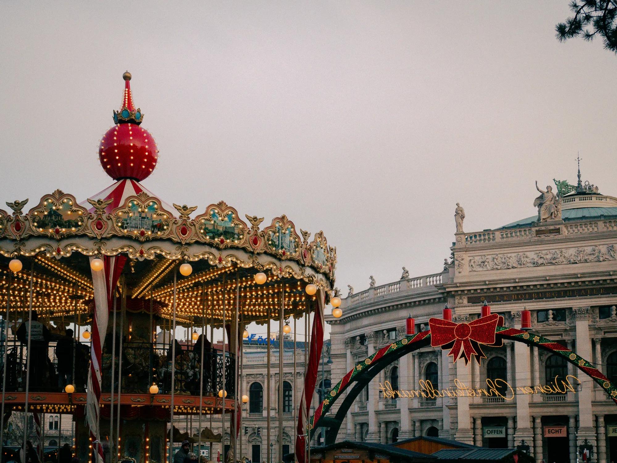 Ein Karussell auf einem Weihnachtsmarkt vor einem klassischen Gebäude.