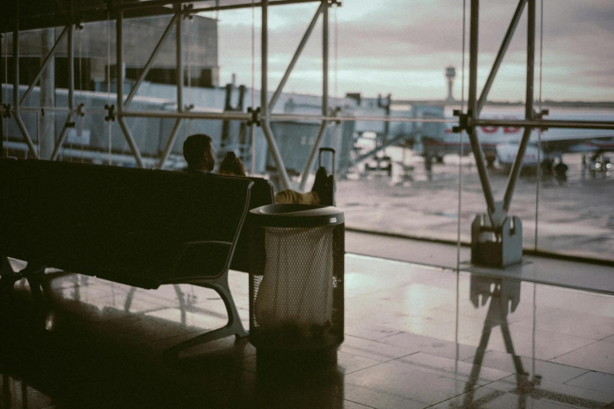 Man sitting inside airport's boarding area.
