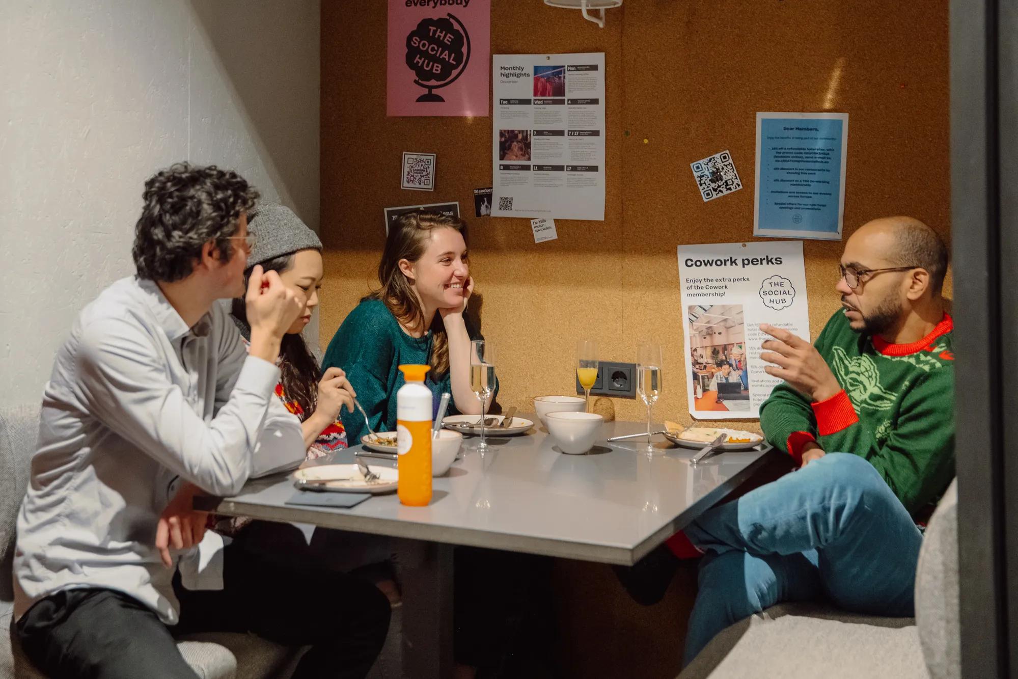 Four people sit around a table at a cafe, eating and talking.
